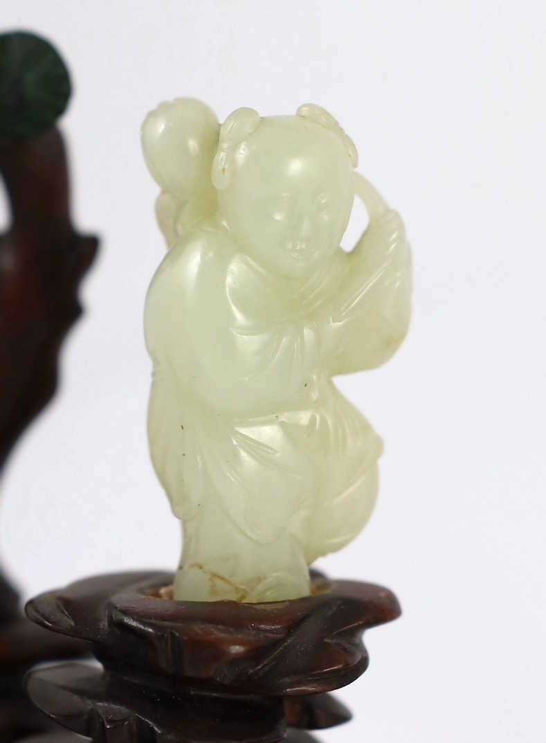 An assembled group of four Chinese pale celadon jade figures, 18th/19th century, displayed on two later wood 'rock-work' stands, total height approximately 19cm high